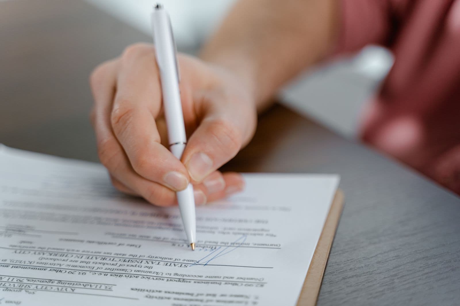 Person reviewing and signing official legal documents at a desk