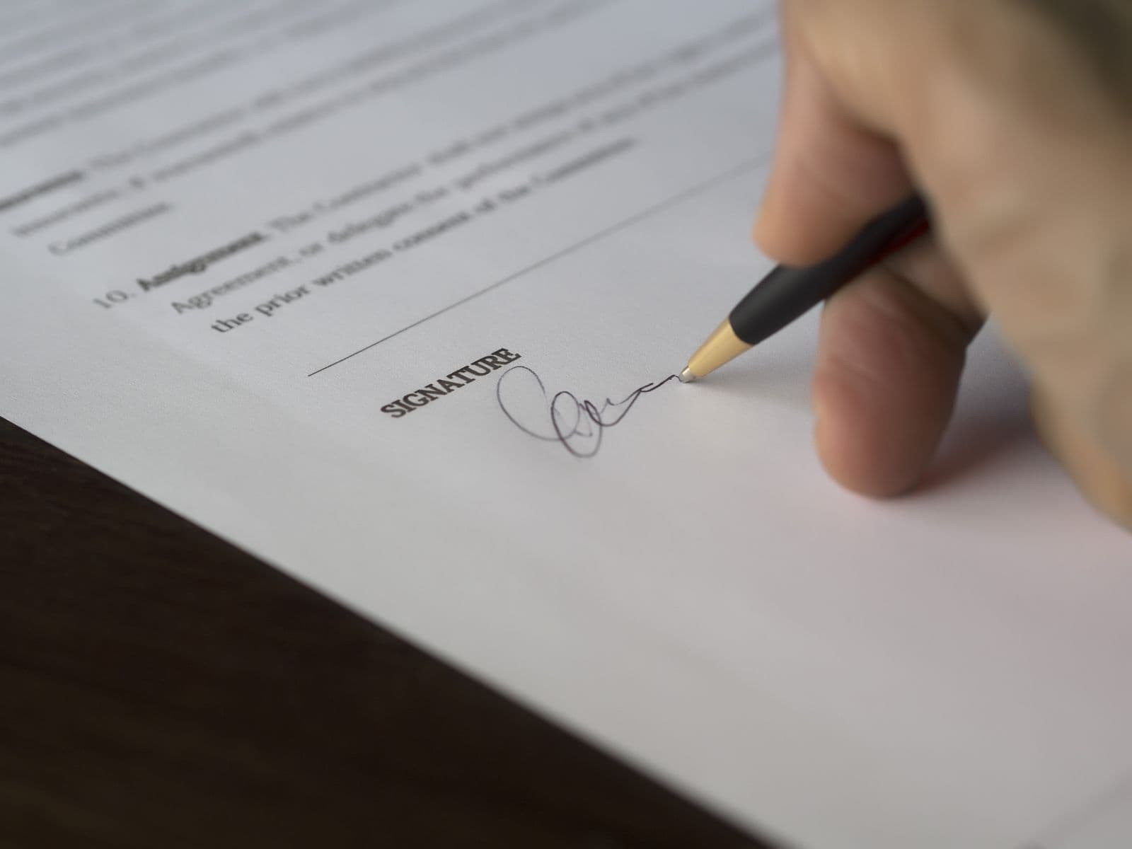 Close-up of a hand signing a legal document with a fountain pen